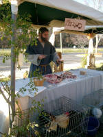 A butcher hawks freshly cut meat, and live fowl & rabbits.